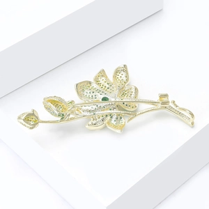 Detailed view of flower brooch with green zircon inlay on a white geometric stand