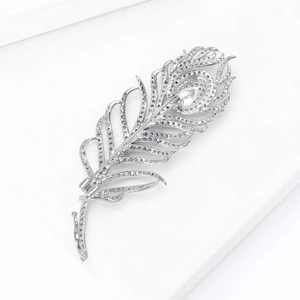 Détail d'une broche plume de paon argentée sertie de zircons sur support blanc
