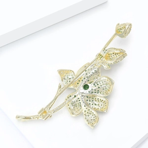 Detailed back view of gold flower brooch showing green stones and safety pin clasp