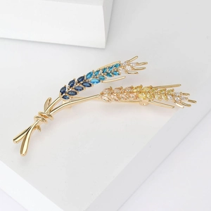 Detail of wheat stalk brooch with colorful gradient zircons on a white display stand