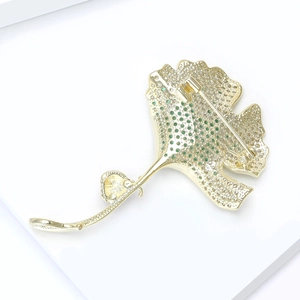 Macro-opname van vergulde ginkgo blad broche met groene zirkoonstenen en speldsluiting