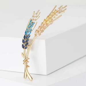 Detail of wheat ear brooch featuring gradient crystals in gold setting on white