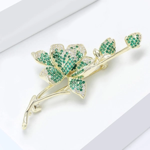 Macro shot of 3D floral brooch featuring green and white zircons with fine micro-inlay finish