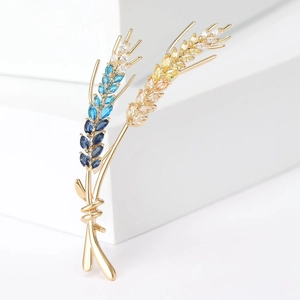 Detailed close-up of wheat brooch with blue and yellow marquise-cut crystals and gold plating