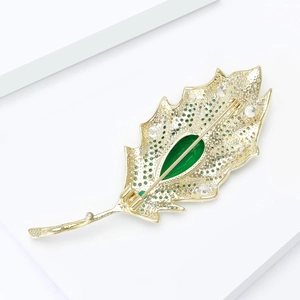Detailed back view of a gold leaf brooch with green zircon inlay and secure pin closure