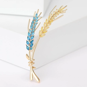 Detailed macro of wheat ear brooch with blue and champagne zircons on gold metal base