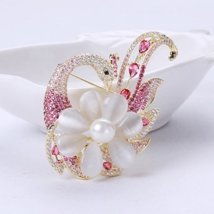 Dettaglio spilla a cigno dorata con petali di opale, strass rosa e cristalli rossi