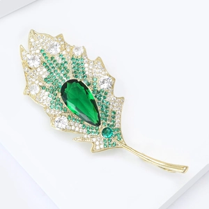 Macro shot of elegant leaf brooch with emerald teardrop stone and shimmering crystals