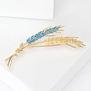 Detail view of wheat brooch with blue and yellow marquise-cut zircon gems in gold plating
