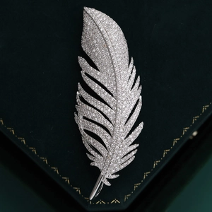 Elegant feather brooch with white zircon pavé in silver finish on green velvet