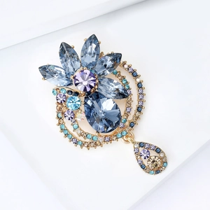 Elegant gold flower brooch with blue and purple gemstones and a teardrop pendant