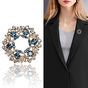 Elegant gold crystal wreath brooch with blue and champagne stones on black blazer