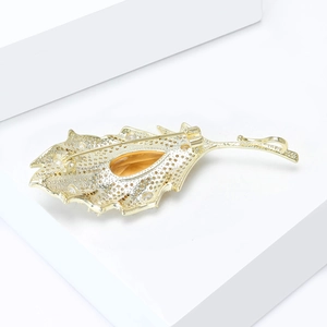 Macro shot of leaf brooch back showing secure safety pin clasp and gold finish
