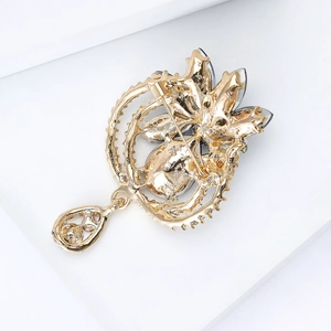 Elegant gold teardrop brooch featuring detailed hollow metalwork and secure pin back