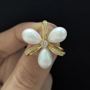 Détail d'un pendentif en forme de fleur avec trois perles de larme et cristal central