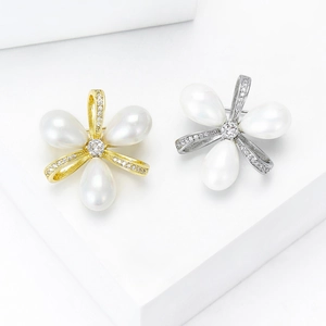 Broches nœuds florales élégantes en or et argent avec perles sur marches blanches