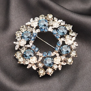 Elegant silver floral wreath brooch with sparkling blue and champagne crystals for suits