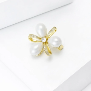 Détail de broche fleur élégante avec perles en goutte et ruban doré serti de cristaux