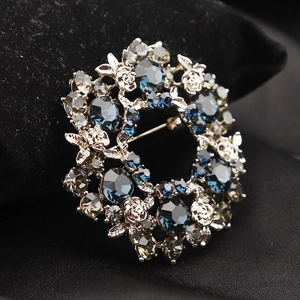 Macro detail of Czech crystal flower wreath brooch with blue and smoke grey stones