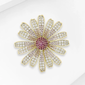 Detail showing elegant daisy brooch with white cubic zirconia and red gem core on gold plating