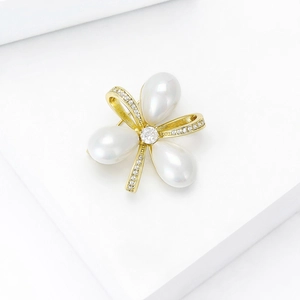 Détail d'élégante broche fleur dorée avec perles blanches en goutte et cristaux brillants