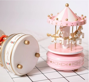 Dettaglio di carillon a giostra rosa con accenti dorati e motivi floreali sulla base