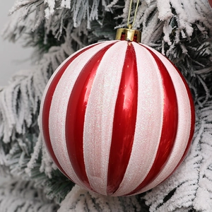 Red and white striped Christmas ball ornament with glitter finish on snowy branch