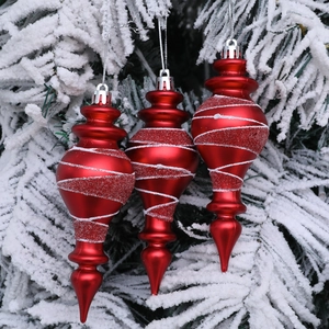 Tre addobbi natalizi rossi con spirali glitterate su rami di pino innevati