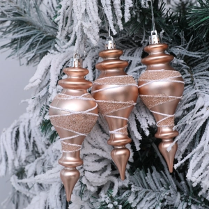 Tre eleganti decorazioni natalizie a mandrino oro champagne appese a rami di pino innevati