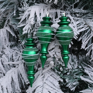 Tre decorazioni natalizie a goccia verde smeraldo con brillantini su rami innevati