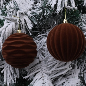 Brown flocked Christmas tree balls with wave and vertical stripes on snowy branches