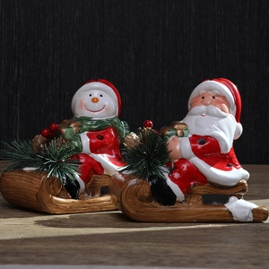 Christmas ceramic Santa and Snowman figurines sitting on a decorative wooden sleigh