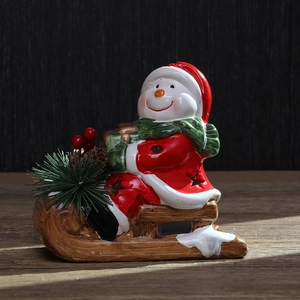 Ceramic snowman figurine on wooden sleigh with festive red jacket and green scarf
