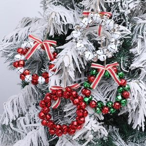 Set of four metal Christmas bell wreaths with striped bows on snowy pine tree branches