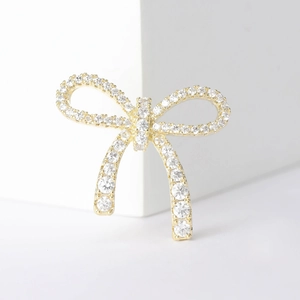Macro view of a gold bow brooch encrusted with sparkling clear zircons and fine details