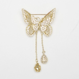 Détail d'une broche papillon dorée avec des ailes en zircone et des glands élégants