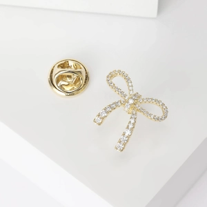 Detail of elegant gold bow brooch with sparkling crystals and metal clutch pin