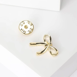 Elegant gold bow brooch with sparkling crystals on a minimalist geometric white stand