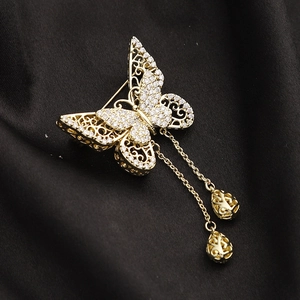 Détail de la broche papillon élégante avec ailes évidées dorées et zircons incrustés