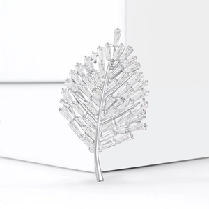 Detailed view of silver leaf brooch with rectangular zircon stones on white display
