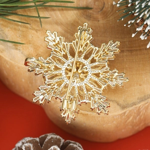Élégante broche flocon dorée avec zircons sur socle bois et décor d'hiver festif