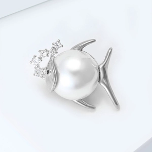 Détail d'une broche poisson avec une perle blanche et des accents en zircon brillant