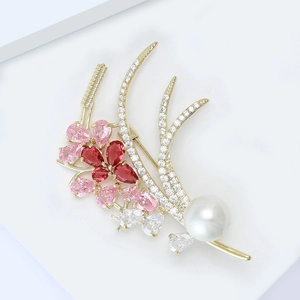 Macro shot of elegant wheat brooch featuring pearls, red gems, and micro-set zircons