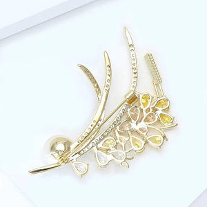 Macro detail of elegant golden wheat brooch with sparkling zircons and a white pearl accent