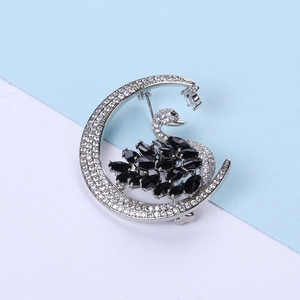 Macro view of silver crescent moon brooch with black swan and inlaid cubic zirconia