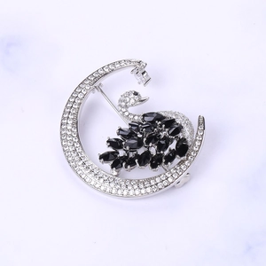 Macro view of silver crescent moon and black swan brooch with zircon micro-pave setting
