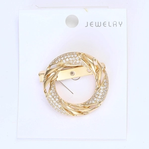 Close-up of golden round scarf buckle with micro-pave cubic zirconia on a white card