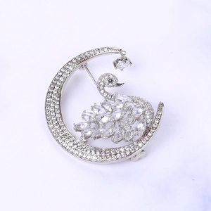 Detailed view of silver moon and swan brooch with shimmering inlaid crystals