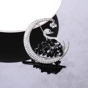 Close-up of silver crystal swan moon brooch with black gems and sparkling white stones