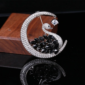 Elegant swan and moon brooch with black crystals and white zircons on dark mirror surface